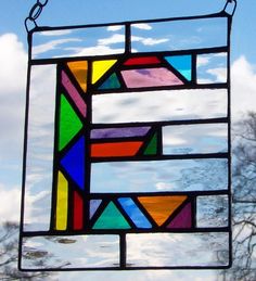 a stained glass window hanging from a chain on a blue sky background with white clouds