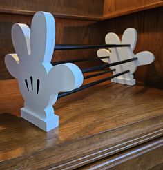 some white paper rabbits are sitting on top of a wooden shelf with black sticks sticking out of them