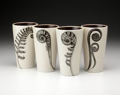 four white cups with black designs on them