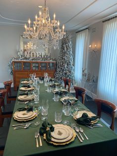 a dining room table is set with place settings and silverware for christmas dinner guests