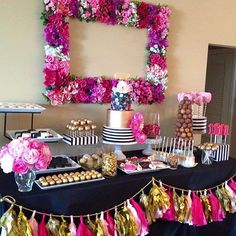 a table topped with lots of desserts and flowers on top of a black table cloth