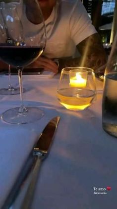 a man sitting at a table with two glasses of wine