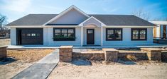 a white house with black garage doors and windows on the front porch is being built