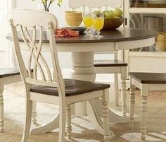 a dining table with four chairs and a bowl of fruit on the table next to it