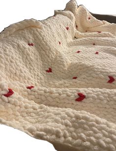 a white crocheted blanket with red hearts on it