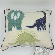 a pillow with two dinosaurs on it, one is green and the other is blue