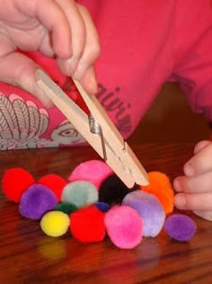 a child is playing with pom poms on the table and cutting them into small pieces