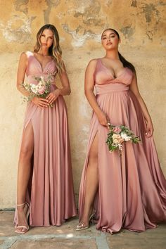 two women standing next to each other wearing dresses with high slits on the sides