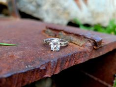 an engagement ring sitting on top of a rusted metal table