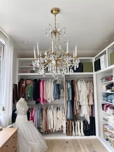 an organized closet with chandelier and clothes