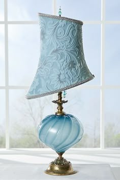 a blue lamp sitting on top of a table next to a window