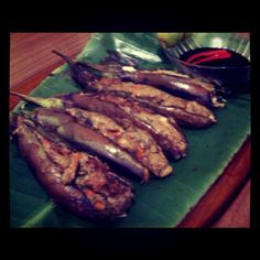 some meat is sitting on a green plate with chopsticks and sauce in the background