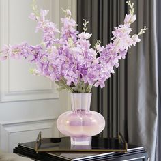 a glass vase with purple flowers on a table