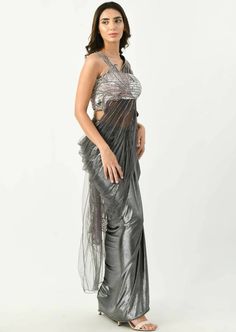 Selena sari is a unique twist to the graceful and the most beloved ethnic attire. The draped sari has fully ornamented blouse in silver. The upper part is embellished with patchwork of lily all over the blouse and pallu. The gun metal color is making this attire to stand out in a crowd and is perfect for any occasion. Evening Draped Blouse Piece With Mirror Work, Silk Draped Blouse With Mirror Work, Glamorous Silk Pre-draped Saree With Mirror Work, Party Embellished Draped Saree, Glamorous Draped Georgette Saree, Sequin Draped Saree For Diwali, Sequin Saree For Diwali, Draped Blouse For Diwali Evening, Draped Blouse For Evening Diwali Celebrations