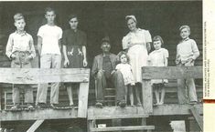 an old black and white photo of people standing on a porch with one child in the foreground