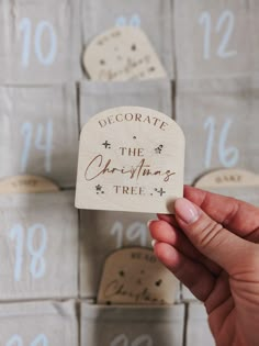 someone holding up a wooden christmas tree ornament