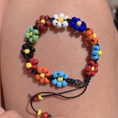 there is a bracelet made out of beads on someone's arm and it looks like they are holding something in their hand