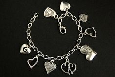 A collection of silver plated decorative heart charms have been dispersed around a shimmering silver plated bracelet chain in this handmade charm bracelet. This heart charm bracelet is then completed with a lobster clasp and a 1/2 inch of chain at the end for adjustable sizing. Charms in this bracelet include an assortment of nine decorative heart charms. ● Sizing ● To determine your bracelet size, do a snug measurement of your wrist's circumference, then add 1/2 an inch. 6 to 6.5 inches (15cm - Adjustable Silver Double Heart Charm Bracelet, Silver Adjustable Double Heart Charm Bracelet, Silver Heart Chain Bracelet For Valentine's Day, Nickel-free Silver Heart Bracelet For Anniversary, Elegant Silver Charm Bracelet With Heart Beads, Silver Metal Chain Bracelet For Valentine's Day, Silver Double Heart Metal Bracelet, Silver Metal Double Heart Bracelet, Elegant Handmade Metal Heart Bracelet