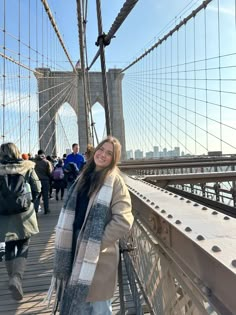 a woman standing on the side of a bridge in front of people walking across it