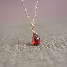 The delicate gold chain has a dark red, drop-shaped pendant made of real garnet. Wear this fine gold chain with the small red garnet with a beige cardigan, a taupe blouse or a black shirt. It sets a beautiful accent. Garnet symbolizes love and friendship. It is also the birthstone for the month of January. Give this pretty necklace as a birthday present to a loved one who was born in January. The necklace is made of 14k gold fill, an allergy-free and durable gold alloy. This is the next best qua Red Dainty Birthstone Necklace, Minimalist Red Gemstone Birthstone Necklace, Dainty Red Birthstone Necklace For Gift, Dainty Garnet Necklace For Gift, Red Gemstone Drop Necklace For Gift, Minimalist Red Birthstone Necklace, Ruby Drop Necklace For Gift, Necklace With Red Stone, Simple Gold Necklace