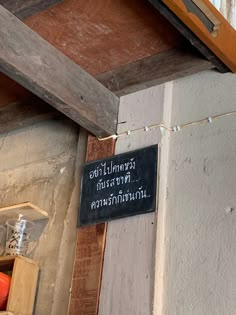 a sign hanging from the side of a building next to a wooden window sill