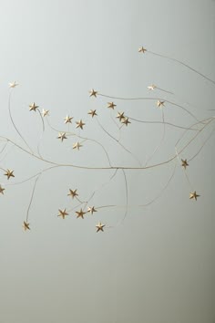 some gold stars are hanging from the ceiling in front of a white wall and floor