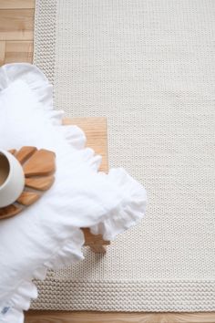 a cup of coffee sitting on top of a white rug next to a wooden table