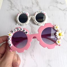 a pair of sunglasses that say sister and flowers on the side, sitting next to each other