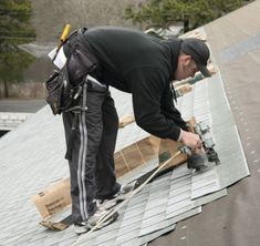 a man working on the roof of a house with tools and equipment in his hands