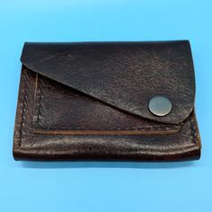 This stylish handmade brown leather wallet is the perfect accessory for anyone. The wallet features a sleek design with a sturdy antique nickel snap closure, keeping your belongings secure while adding a touch of sophistication to your look.  With a single card slot on the front and a spacious main compartment, this wallet is both practical and fashionable, making it ideal for everyday use. Upgrade your accessory game with this timeless piece that will never go out of style. Length:  4.75" Width Brown Leather Wallet, Handmade Leather Wallet, Money Clip Wallet, Handmade Leather, Leather Handmade, Out Of Style, Purse Wallet, Timeless Pieces, Snap Closure