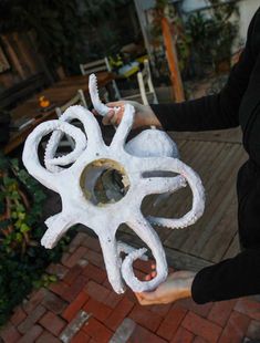 a person holding a white piece of art made out of clay on brick walkways