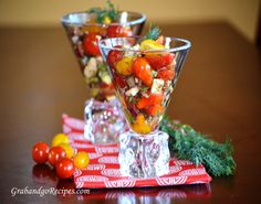 two glasses filled with fruit and vegetables on top of a table