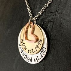 Custom grandma necklace for a new grandma or one that's well established. Show your grandparent pride with this "established" mom and grandma necklace.1" handstamped silver alkeme tag is stamped "Grandma est." with date you became (or will become) a grandma. 3/4" solid brass disc stamped "Mom est." with date you became a mom. 1/2" copper heart charm.All pieces are hand stamped letter by letter in true artisan style.  Edges are beveled and each has a brushed satin finish.Hangs from a .925 sterlin Round Pendant Necklace With Hallmark For Mother's Day, Hand Stamped Name Necklace For Mother's Day, Personalized Necklace For Mother's Day Gift, Custom Round Necklace For Anniversary And Mother's Day, Custom Round Necklace For Anniversary On Mother's Day, Customizable Keepsake Jewelry For Mother's Day, Mother's Day Keepsake Jewelry With Hallmark, Stamped Charm Necklaces For Mother's Day, Hand Stamped Round Necklace For Mother's Day