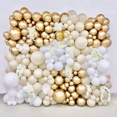 a bunch of white and gold balloons on top of each other