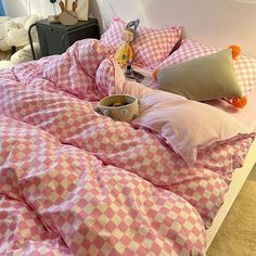 a pink and white checkered comforter on a bed with two stuffed animals in the corner