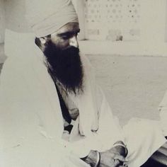 an old black and white photo of a man with a long beard sitting on the ground