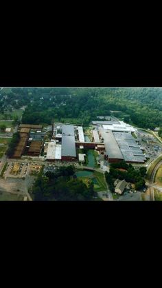 an aerial view of a large industrial building in the middle of a green area with trees