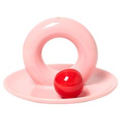 a pink object sitting on top of a white plate with a red ball in it