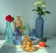 several different colored vases with flowers in them