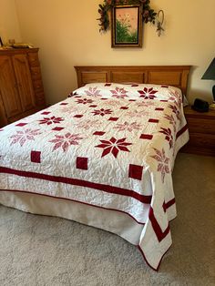 a bed with a white and red bedspread on top of it in a bedroom