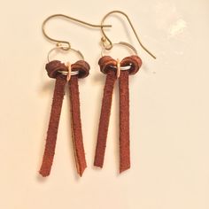 two pairs of brown leather earrings hanging from hooks