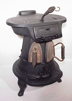 an old fashioned stove is sitting on a white surface with a hook in the middle