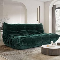 a large green couch sitting on top of a living room floor next to a window