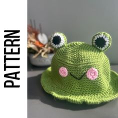 a green crocheted hat with eyes and ears on it, sitting on a table