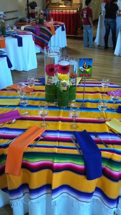 the table is set with colorful napkins and place settings for guests to sit at