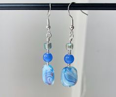 blue and white earrings with glass beads hanging from hooks on a metal hook - chain