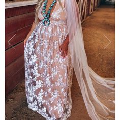 a woman in a wedding dress and veil posing for a photo on the side of a barn