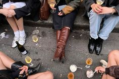 several people sitting on the steps with drinks and snacks in their hands as they drink from wine glasses