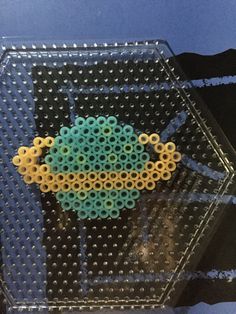 a beaded object sitting on top of a glass table next to a blue wall