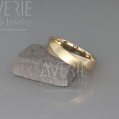 two gold wedding bands sitting on top of a rock